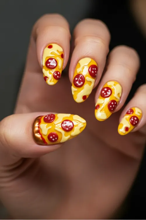 Bright nail art with pepperoni pizza slice designs in vibrant yellow and red tones."