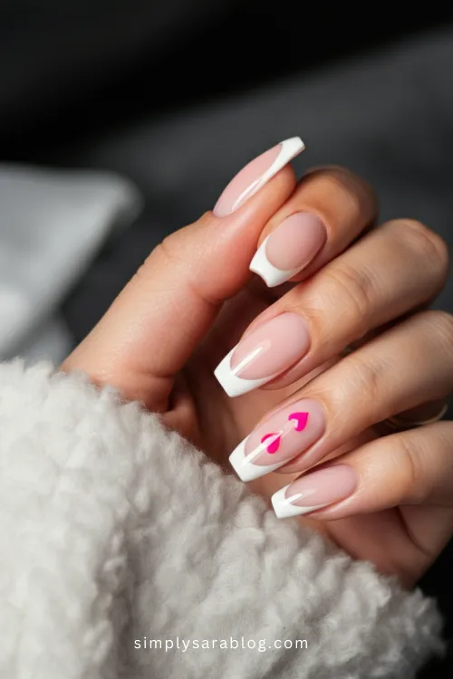 Close-up of pink Valentine’s Day nail art with hearts and glitter.